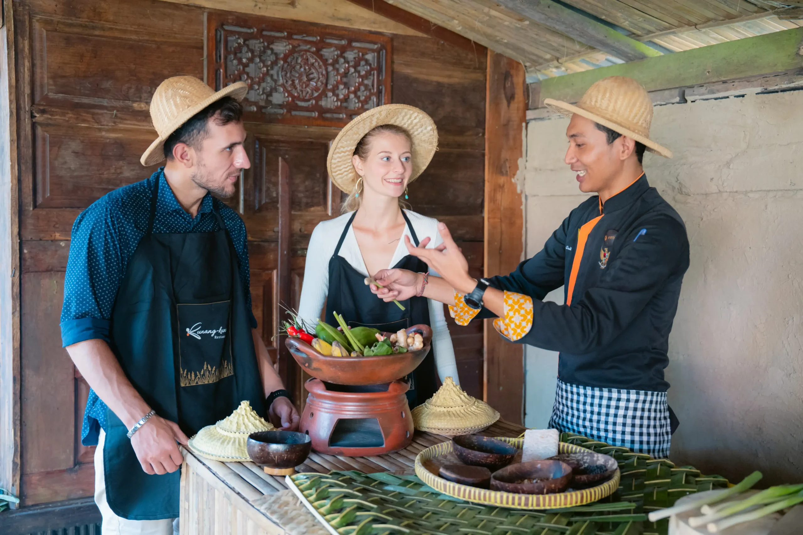 Guests cooking with a local chef in a traditional Balinese kitchen